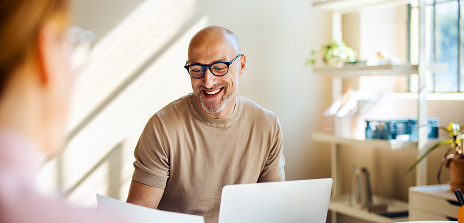 Homme souriant en rendez-vous professionnel devant un ordinateur portable.