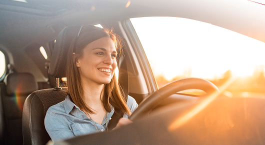 Conductrice souriante au volant d’une voiture, associée aux avantages du rachat de véhicule en fin de contrat.