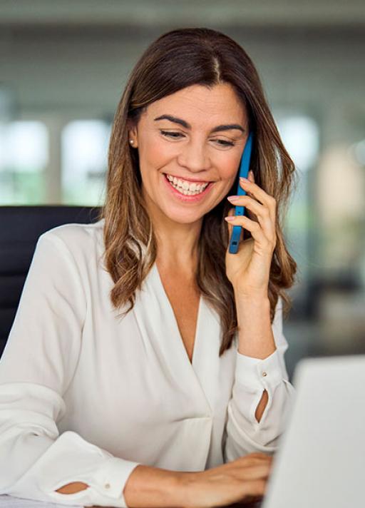 Femme souriante au télephone travaillant sur un ordinateur portable