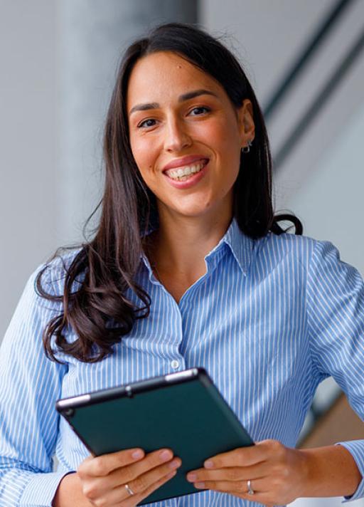 Femme souriante tenant une tablette numérique au bureau