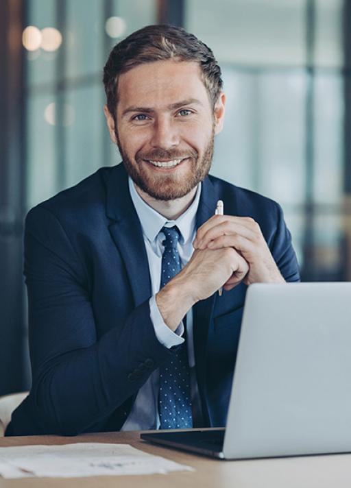 Un homme avec un ordinateur devant lui sourit