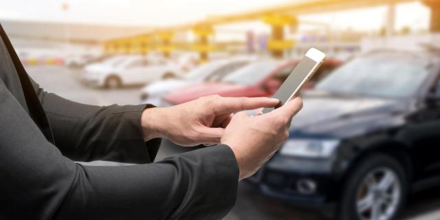 Jeune homme réservant une voiture en autopartage sur son téléphone