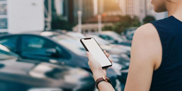 Jeune femme réservant sur son téléphone une voiture en autopartage