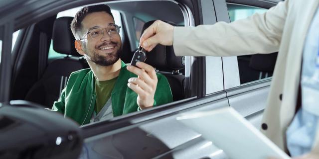 Homme au volant qui récupère les clés de sa nouvelle voiture