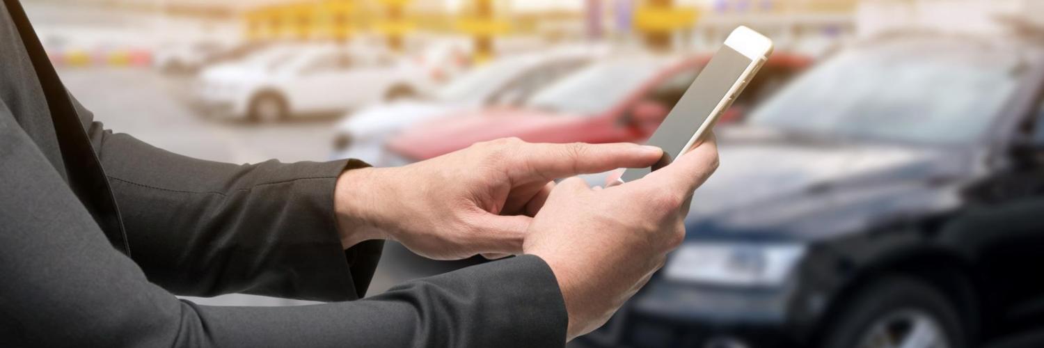 Jeune homme réservant une voiture en autopartage sur son téléphone
