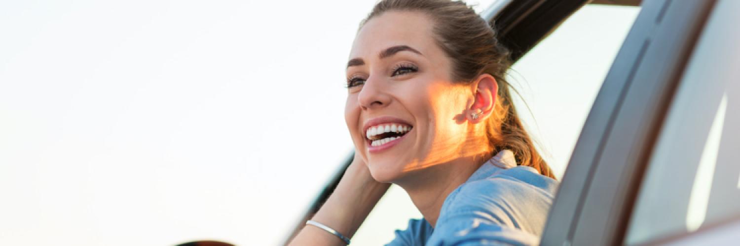 Visuel femme souriante à la fenêtre d'une voiture