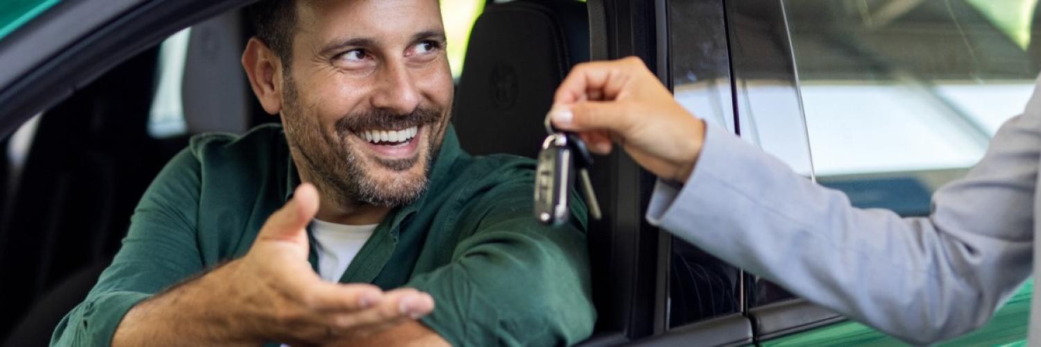 Un homme, installé au volant, récupère ses nouvelles clés de voiture.