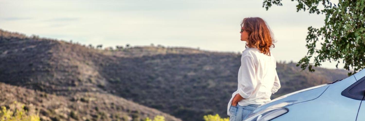 visuel femme adossée à sa voiture