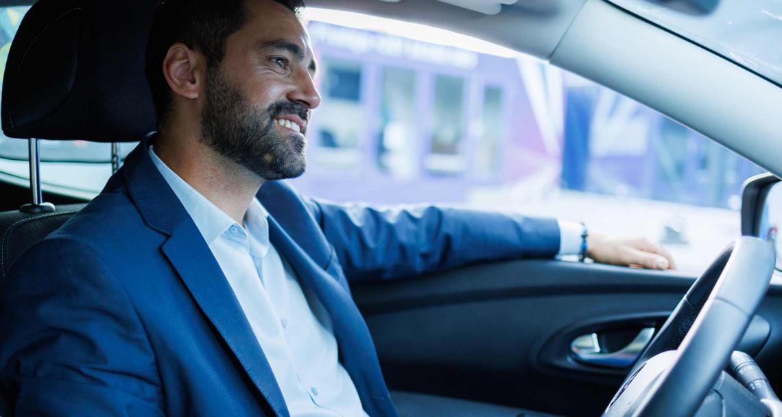 Un homme est assis dans sa voiture souriant