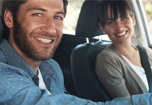 Un homme et une femme sourient en voiture