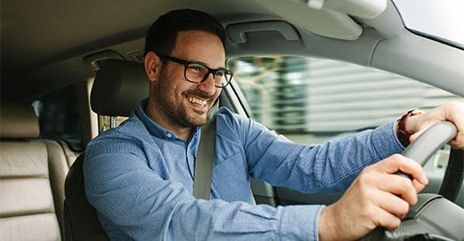 Un homme souriant au volant d'une voiture