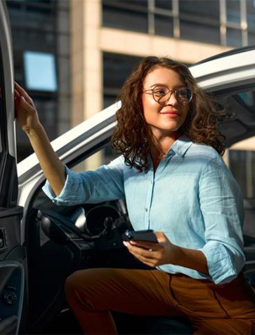 Une femme sourit en sortant d'un véhicule