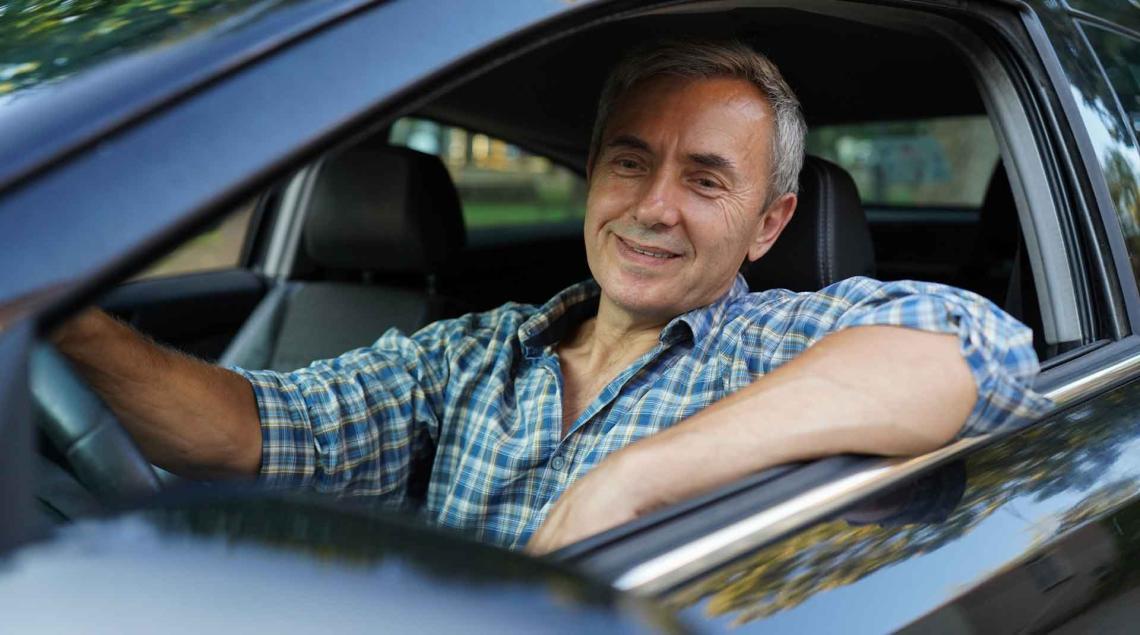 Homme souriant au volant d'une voiture