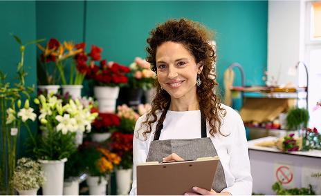 Fleuriste souriante tenant un carnet dans sa boutique de fleurs.