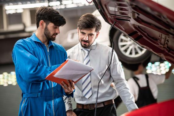 Géolocaliser un garage partenaire Deux hommes dans un garages regardant un devis d'entretien